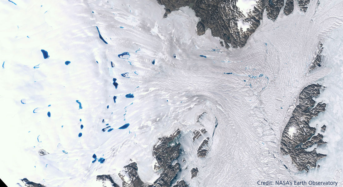 Satellit farvefoto taget over gletsjeren Zachariæ Isstrøm i Nordøstgrønland om foråret (blå farver er smeltevandssøer, grå er klipper/bjerge). Foto: NASA